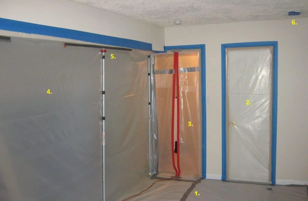 Mold remediation containment barrier with plastic sheeting, poles, and sealed doorways to prevent mold spore spread during the remediation process.
